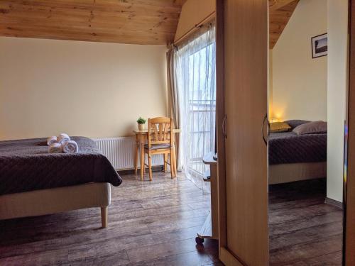 een slaapkamer met 2 bedden en een tafel met een stoel bij Guest House Kamara in Panevėžys