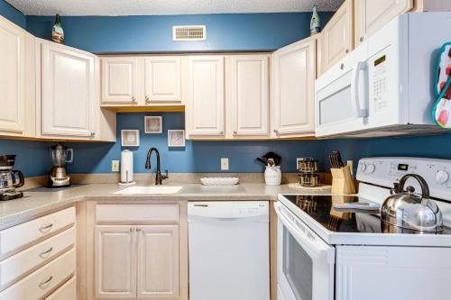 a kitchen with white cabinets and blue walls at Marylander Condominiums, 90 steps from the beach in Ocean City