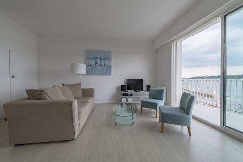 un salon avec un canapé, une table et des chaises dans l'établissement Appartement vue mer, à Bénodet