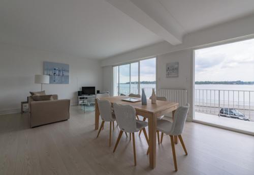 a dining room with a table and chairs in a living room at Appartement vue mer in Bénodet