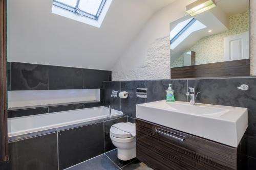 a bathroom with a sink and a toilet and a mirror at Cunsey, Penthouse Apartment Windermere in Windermere