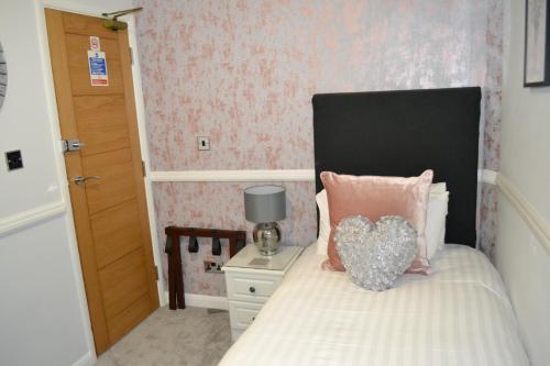 a bedroom with a bed with a heart pillow on it at Harriet House B&B in Canterbury