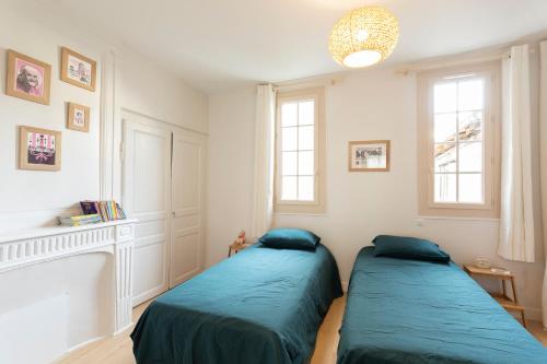 deux lits dans une chambre avec deux fenêtres dans l'établissement LE CARPE DIEM, à Tours