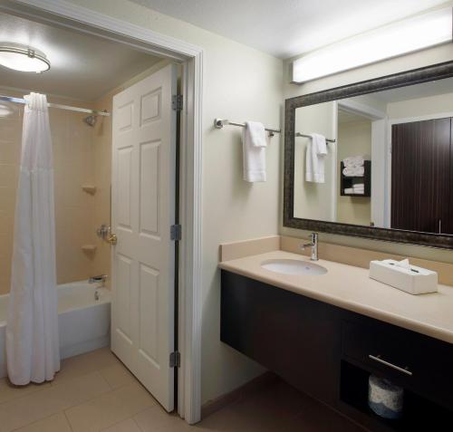 Staybridge Suites Fayetteville, an IHG Hotel في فايتيفيل: حمام مع حوض ومرآة وحوض استحمام