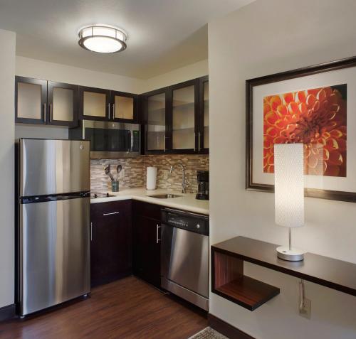 a kitchen with a refrigerator and a table with a lamp at Staybridge Suites Fayetteville by IHG in Fayetteville