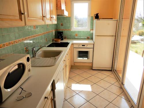 a kitchen with a sink and a white refrigerator at La Balme in Loubressac