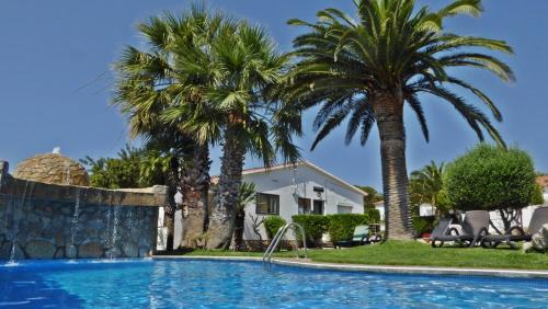 a swimming pool with palm trees and a house at BUNGALOW-PARK LAS DOS TARTANAS in Hospitalet de l'Infant