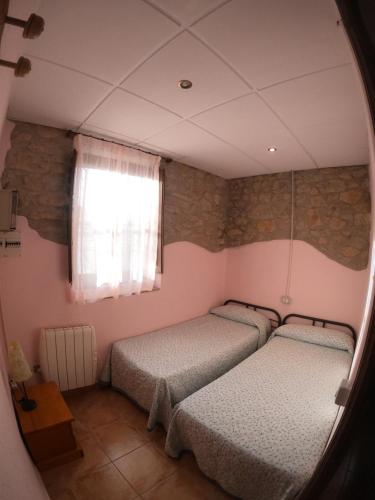 xalet l’avella 2 في Catí: سريرين في غرفة صغيرة مع نافذة