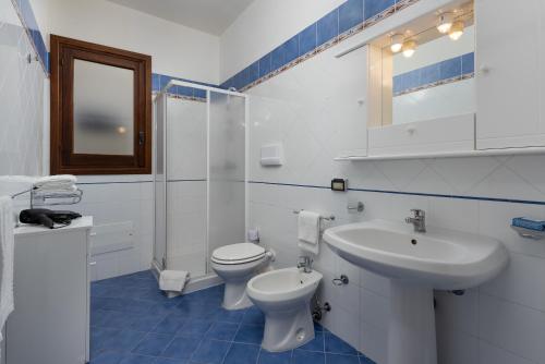 a white bathroom with a toilet and a sink at Le Palme Di Conturrana in San Vito lo Capo