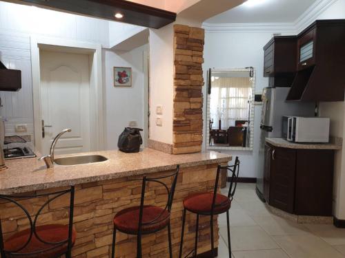 a kitchen with a counter with three stools at a kitchen island at Delta Sharm Apartment in Sharm El Sheikh