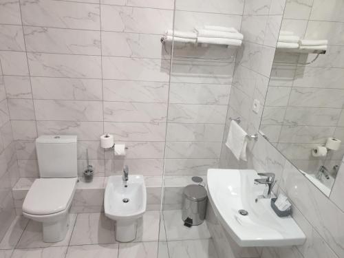 a white bathroom with a toilet and a sink at LEX Trend Hotel in Irpin'
