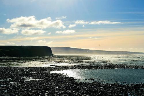 a beach with the ocean and a rocky shore at Station House Bed & Breakfast in Ennistymon