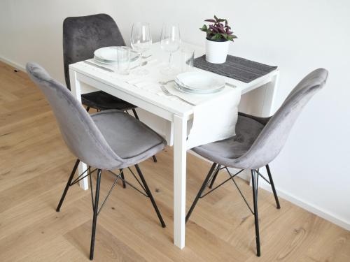 a white dining room table with two chairs and a white table at Apartments Sabine K in Merano
