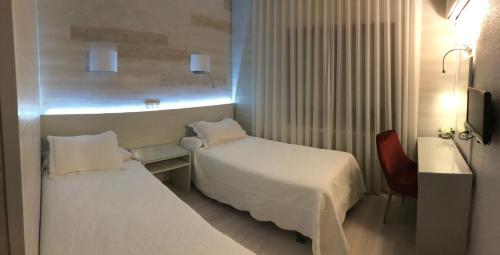 Habitación de hotel con 2 camas y escritorio en Hostal la Parrilla en Tudela