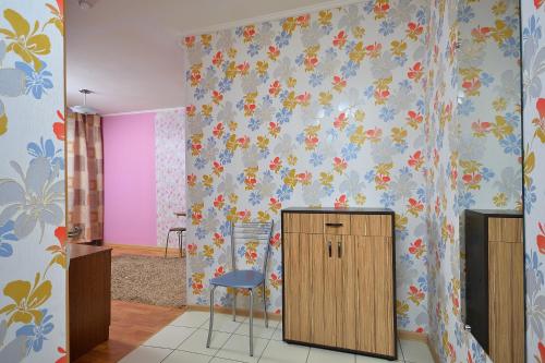 オムスクにあるOmskSutki Apartments on Tsyolkovskogo st.の青とピンクの壁の客室で、キャビネットと椅子が備わります。
