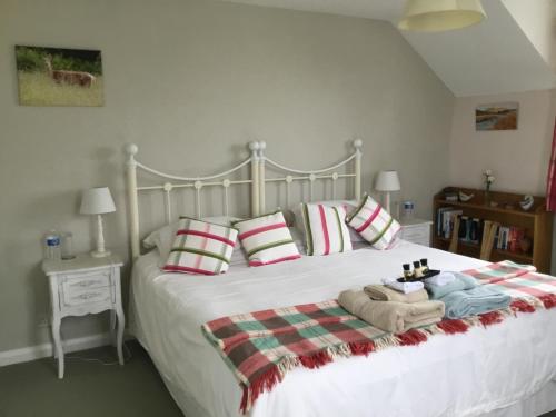 a bedroom with a large white bed with blankets and pillows at Monks Cleeve in Exford