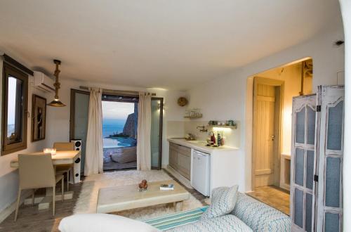 a living room with a table and a kitchen with the ocean at Amallini Suites Mykonos in Super Paradise Beach