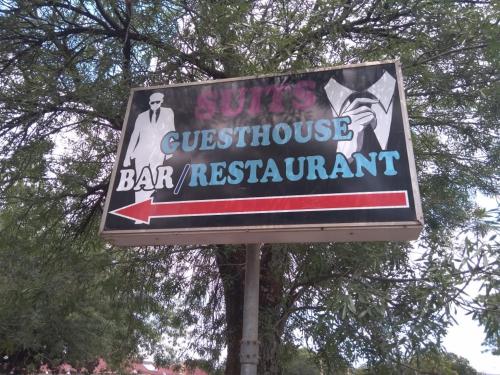 a sign for a bar restaurant in front of a tree at Suits Guest house & bar in Carletonville