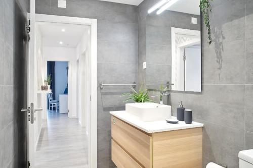 La salle de bains est pourvue d'un lavabo blanc et d'un miroir. dans l'établissement Alegria 79 - Fabulous 3 Bedroom House, à Coimbra