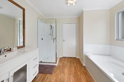 La salle de bains est pourvue d'une baignoire, d'un lavabo et d'un miroir. dans l'établissement Tower Lodge Motel, à Invercargill