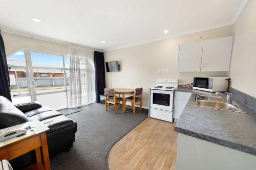 a kitchen with a table, chairs and a microwave at Tower Lodge Motel in Invercargill