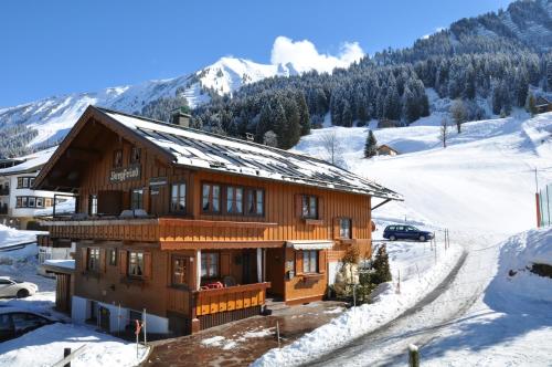 ein Haus im Schnee mit Bergen im Hintergrund in der Unterkunft Das Bergfried - Urlaub zentral und ruhig! in Riezlern