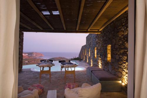 a room with a table and chairs and a stone wall at Amallini Suites Mykonos in Super Paradise Beach