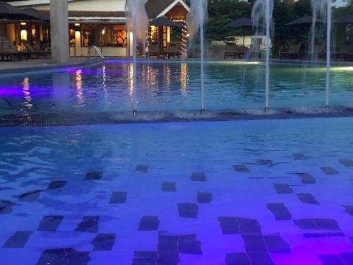 a pool with a fountain at night with purple lights at Ameg Lodge Kilimanjaro in Moshi