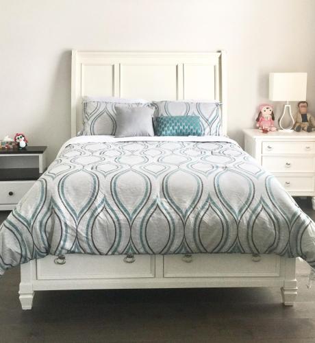 a bedroom with a bed with a blue and white comforter at Comfortable private space in Pickering