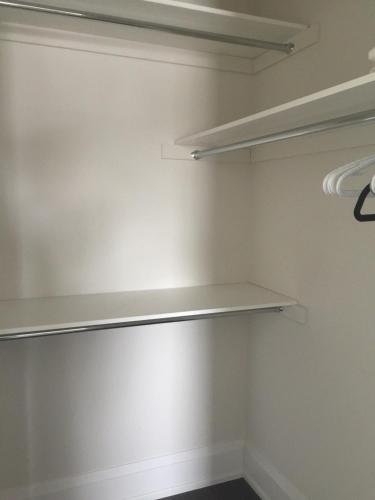 a walk in closet with white walls and shelves at Comfortable private space in Pickering