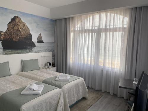a hotel room with two beds and a window at Golden Beach Guest House & Rooftop Bar in Faro