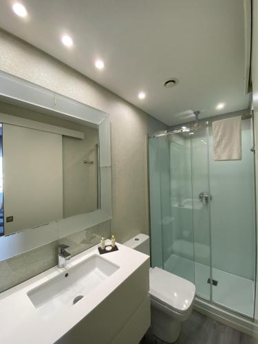 a bathroom with a sink and a shower and a toilet at Golden Beach Guest House & Rooftop Bar in Faro