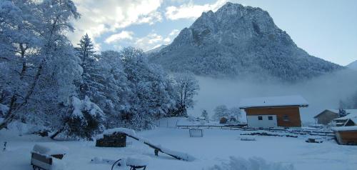 a snow covered mountain in front of a house at Ufem Egg Ferienwohnungen in Innertkirchen