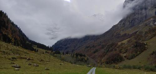a road in the middle of a mountain with clouds at Ufem Egg Ferienwohnungen in Innertkirchen