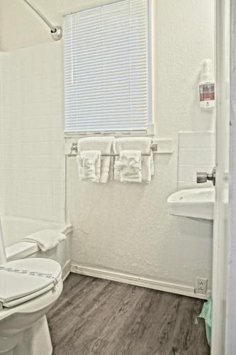 a white bathroom with a toilet and a sink at Arbor Inn Motel Oakridge in Oakridge