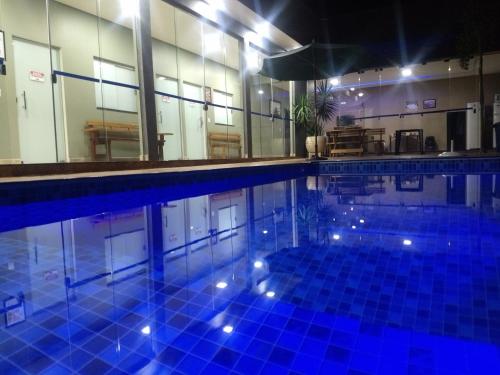 a large swimming pool with blue tiles in a building at Casa Família Porto in Olímpia