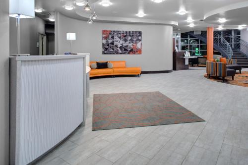 an office lobby with an orange couch and a rug at Holiday Inn Windsor - Wine Country by IHG in Windsor