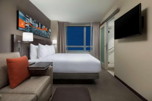 a hotel room with a bed and a couch at Hyatt Place New York City - Times Square in New York
