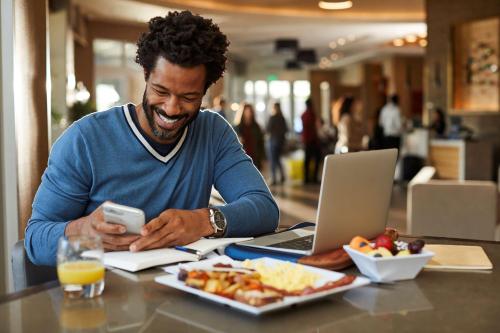 a man sitting at a table with a plate of food and a laptop at Hyatt Place New York City - Times Square in New York