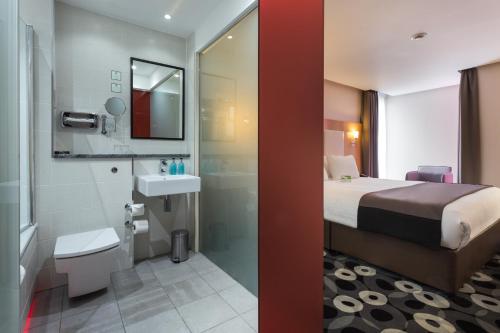 a hotel room with a bed and a bathroom at Holiday Inn Sittingbourne by IHG in Sittingbourne