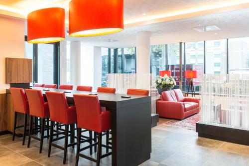 a conference room with a bar with red chairs at Bastion Hotel Amsterdam Airport in Hoofddorp