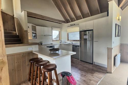 a kitchen with white cabinets and a counter with stools at Dragonfly Chalet in Dinner Plain