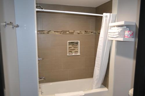 a bathroom with a shower with a bath tub at Bell Gardens Inn Los Angeles - Bell Gardens in Bell Gardens