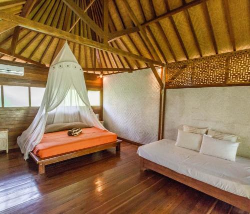 a room with two beds and a hammock in it at Rhipidura Bungalows by Phocéa in Pemuteran