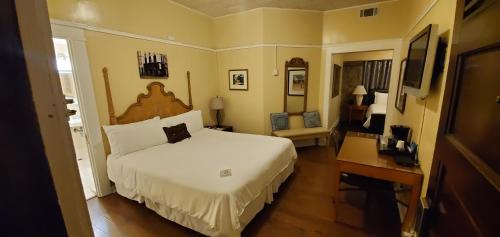 a bedroom with a large white bed and a desk at Glen Tavern Inn in Santa Paula