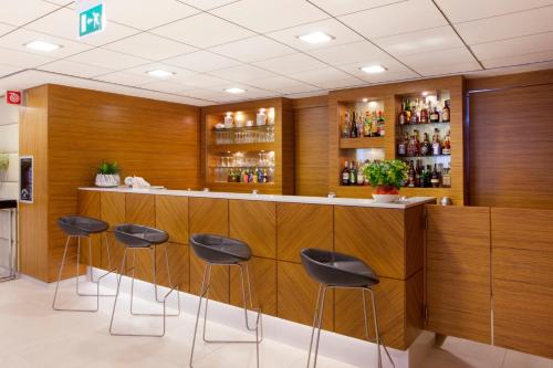 a bar with black stools in a room at Holiday Inn Salerno-Cava De' Tirreni by IHG in Cava deʼ Tirreni