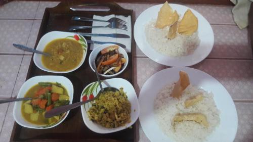a tray of food with rice and different types of food at Vibushan Guest House in Nilaveli