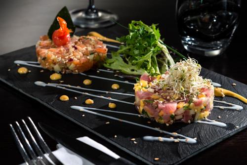 a black plate with food on a table at Holiday Inn Toulouse Airport by IHG in Blagnac
