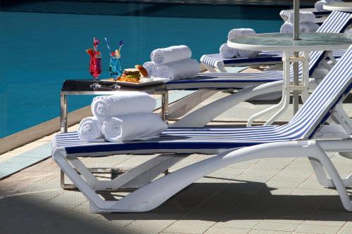 two lounge chairs with towels and a table next to a pool at Holiday Inn Tabuk by IHG in Tabuk