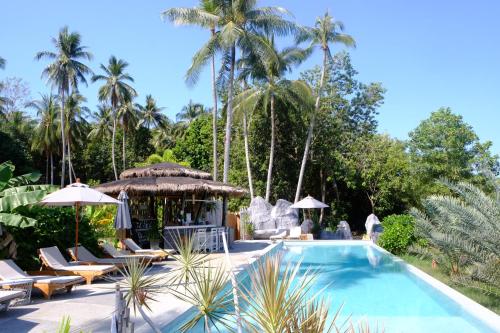 a swimming pool with lounge chairs and palm trees at Awana Villa Resort Yaonoi - SHA Extra Plus in Ko Yao Noi
